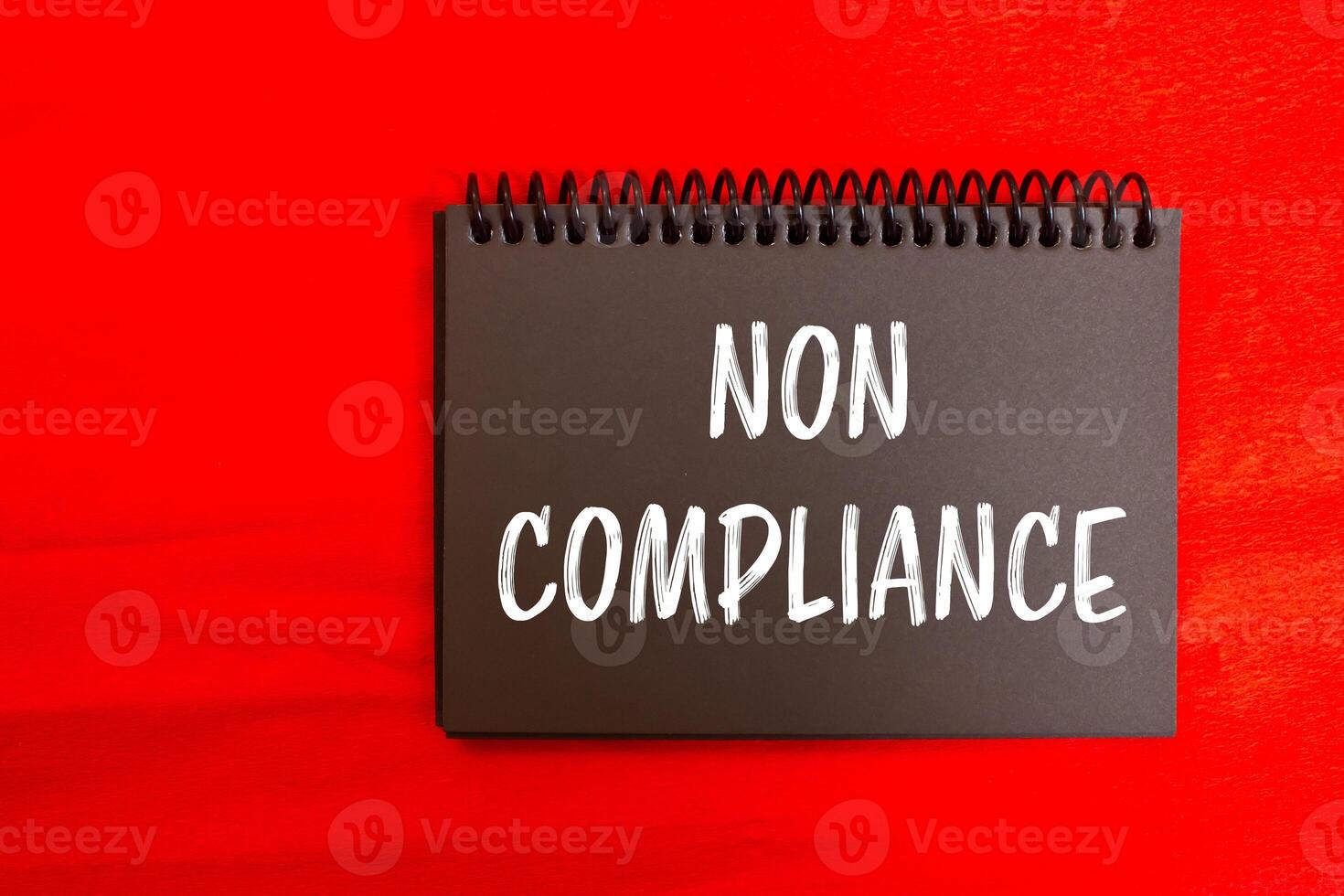 Non compliance message written on black notebook page with red background. Conceptual non compliance symbol. Copy space. photo