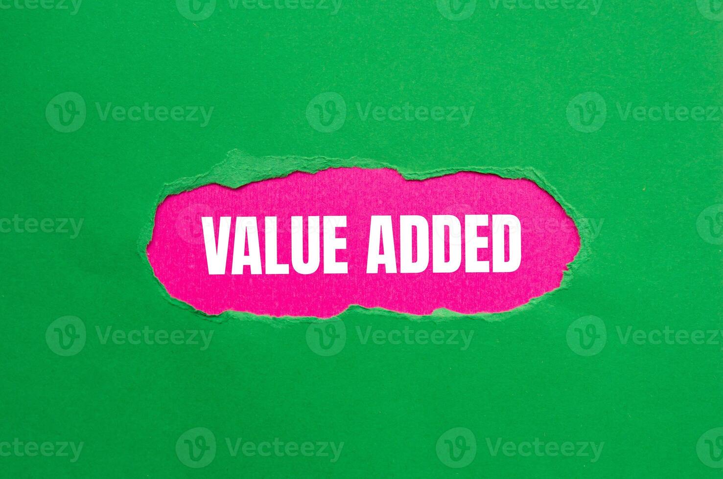 Value added message written on ripped torn green paper with pink background. Conceptual value added symbol. Copy space. photo
