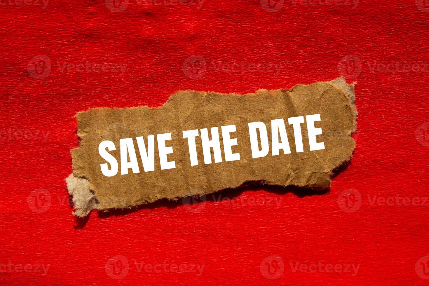 Save the date message written on ripped torn cardbaord paper piece with red background. Conceptual save the date symbol. Copy space. photo