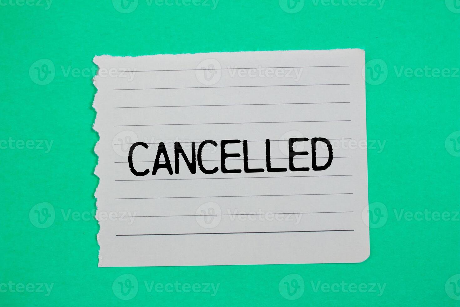 Cancelled message written on ripped torn paper piece with green background. Conceptual cancelled symbol. Copy space. photo