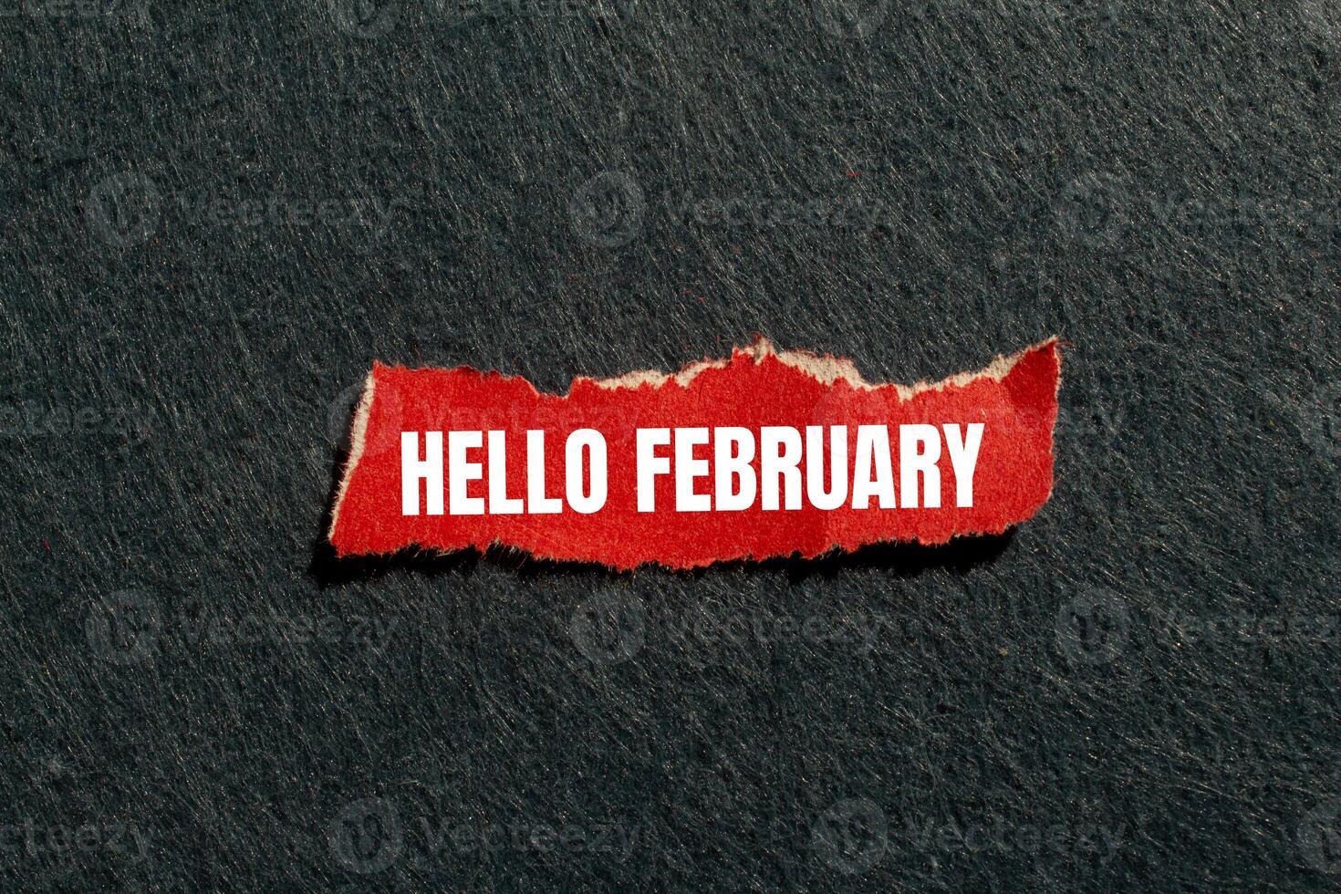 Hello february message written on ripped torn red paper piece with gray background. Conceptual hello february symbol. Copy space. photo