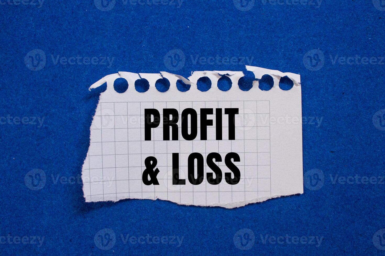 Profit and loss message written on ripped torn paper piece with blue background. Conceptual profit and loss symbol. Copy space. photo
