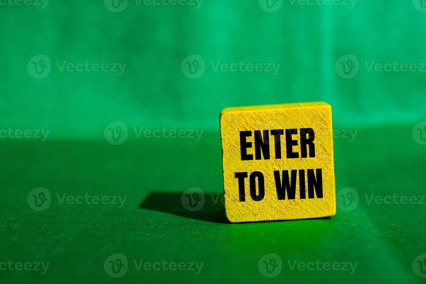 Enter to win message written on yellow wooden cube with green background. Conceptual enter to win symbol. Copy space. photo