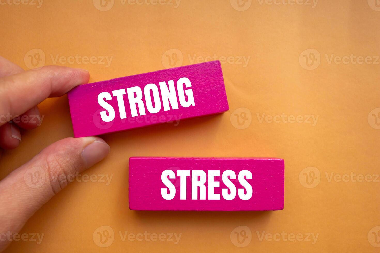 Strong stress message written on pink wooden blocks with orange background. Conceptual strong stress symbol. Copy space. photo
