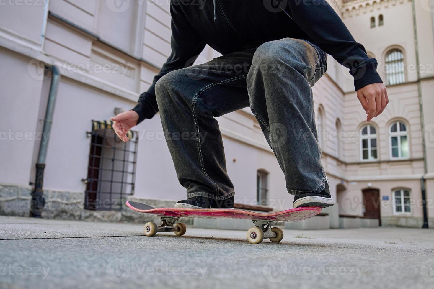 Skateboarder doing trick at urban street. Close up of skater wearing baggy jeans balancing on skateboard. Concept of youth subculture photo