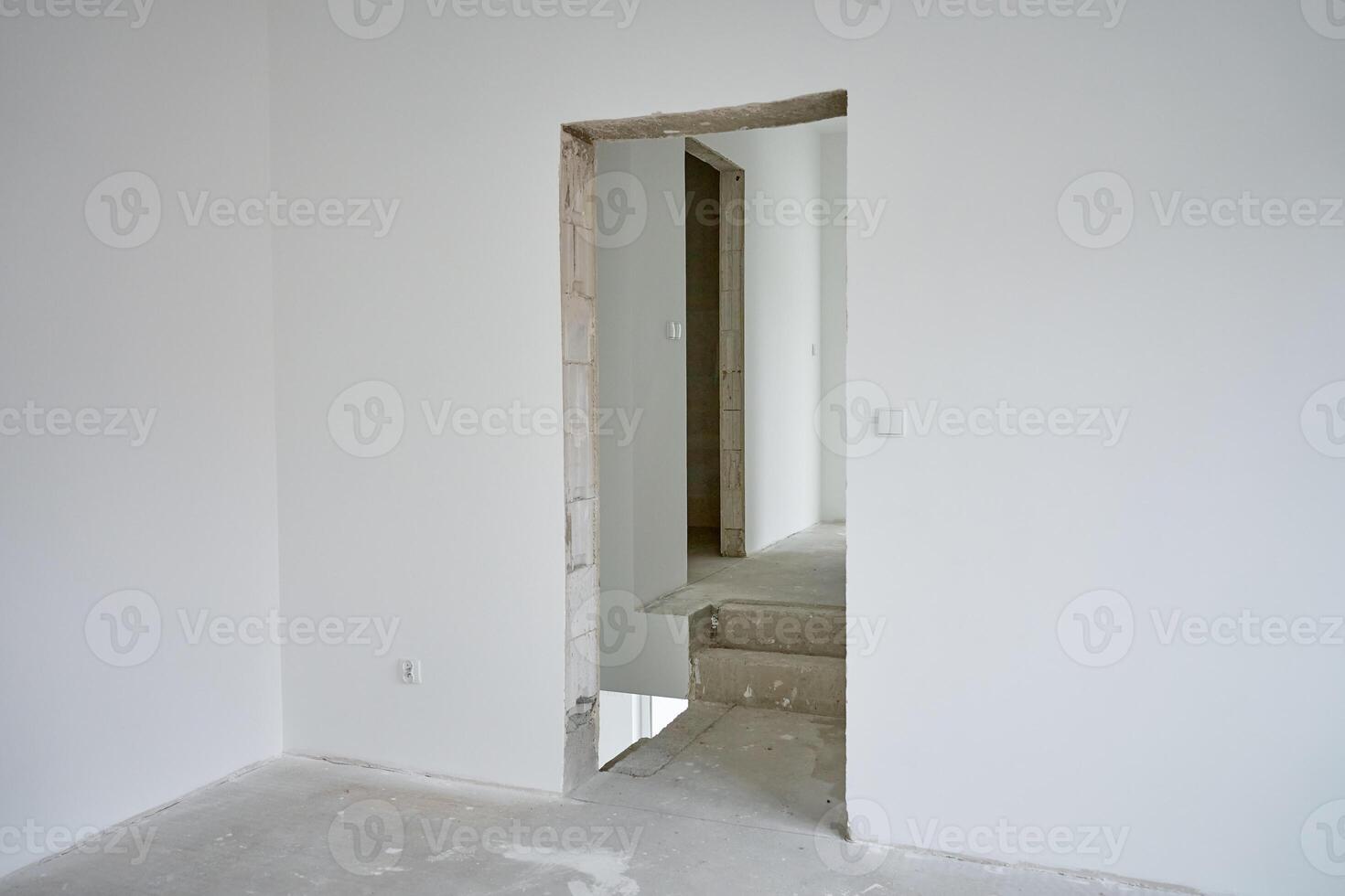 Empty apartment with white walls and concrete floor undergoing renovation. Interior of building under construction photo