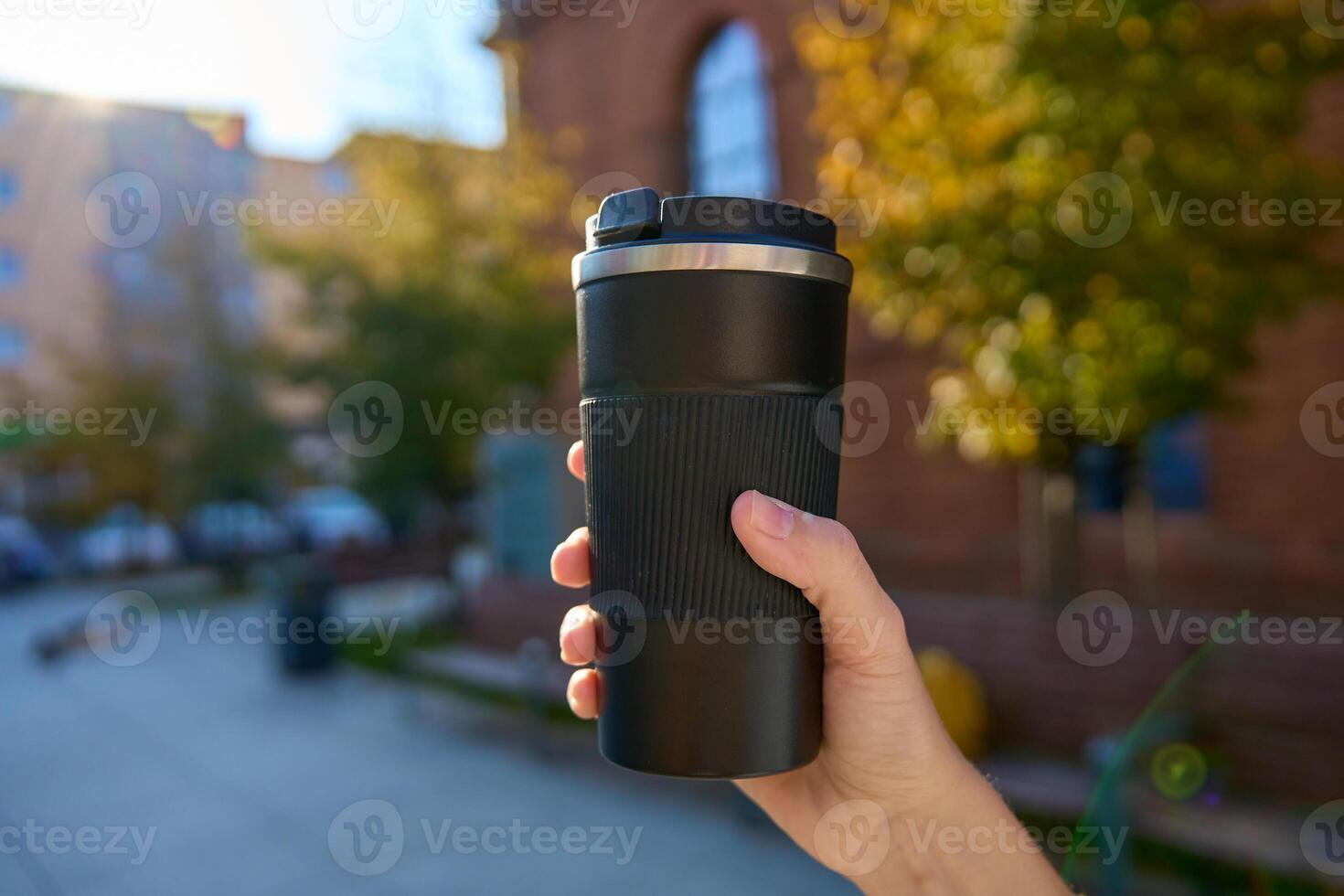 Woman holding reusable coffee cup on blurred autumn background. Concept of sustainable and eco-friendly living photo