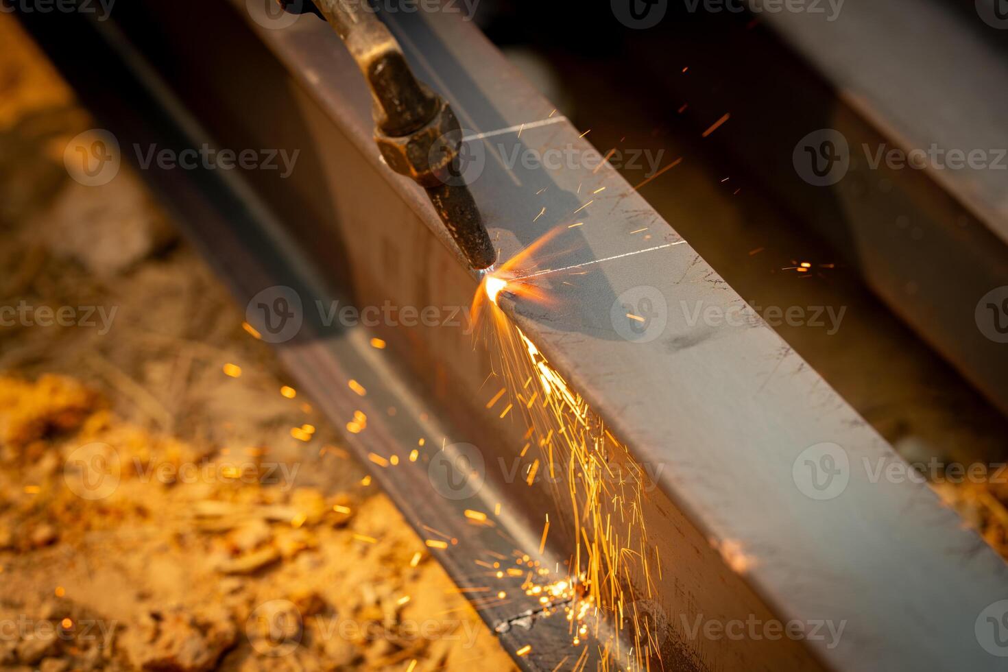 Skilled welder cuts metal with a gas torch in industrial workshop. Sparks fly during precision fabrication process. Craftsman control and expertise in metalworking. Gas torch cuts through steel. photo