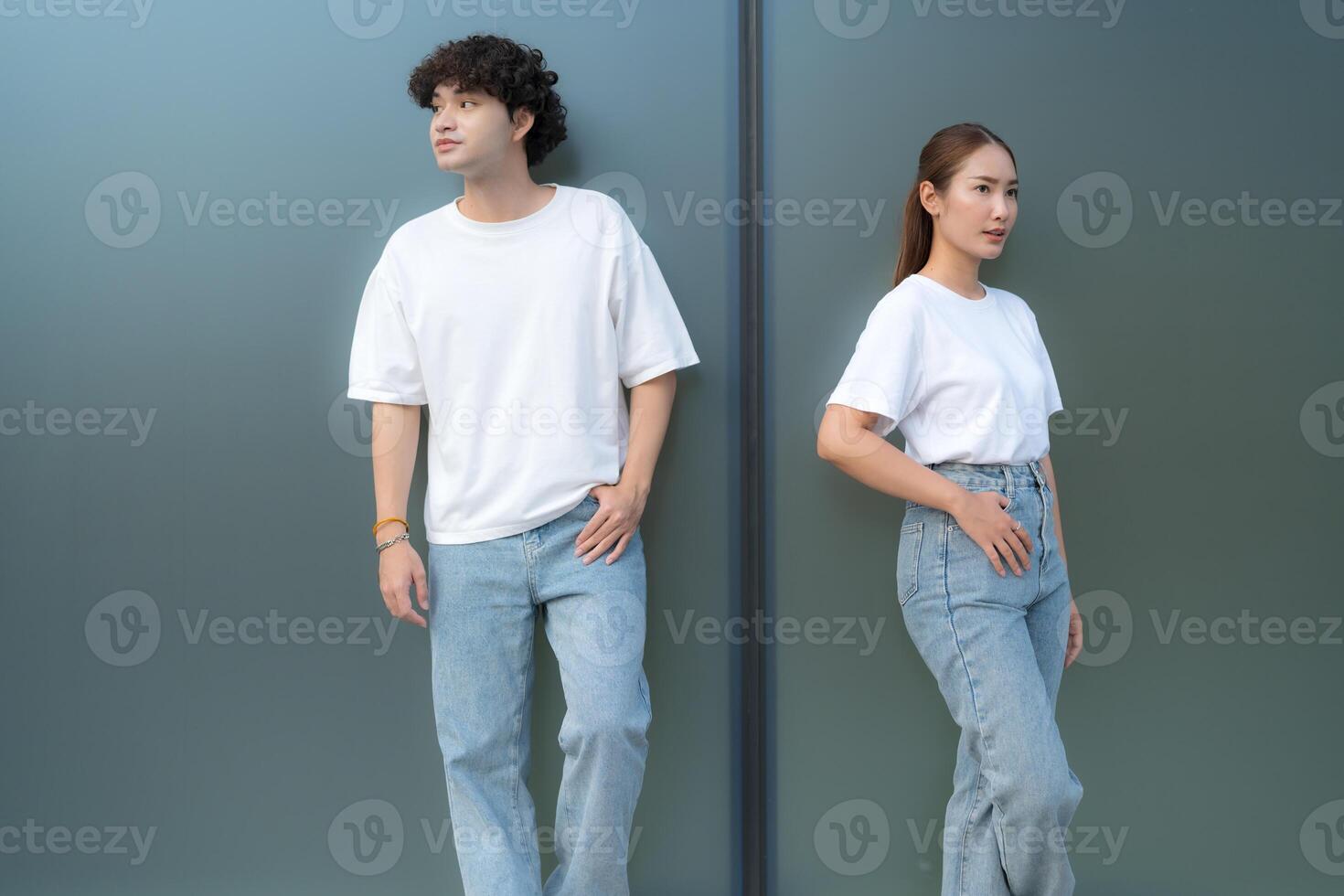 Young couple wearing white t-shirts and jeans posing against a wall photo