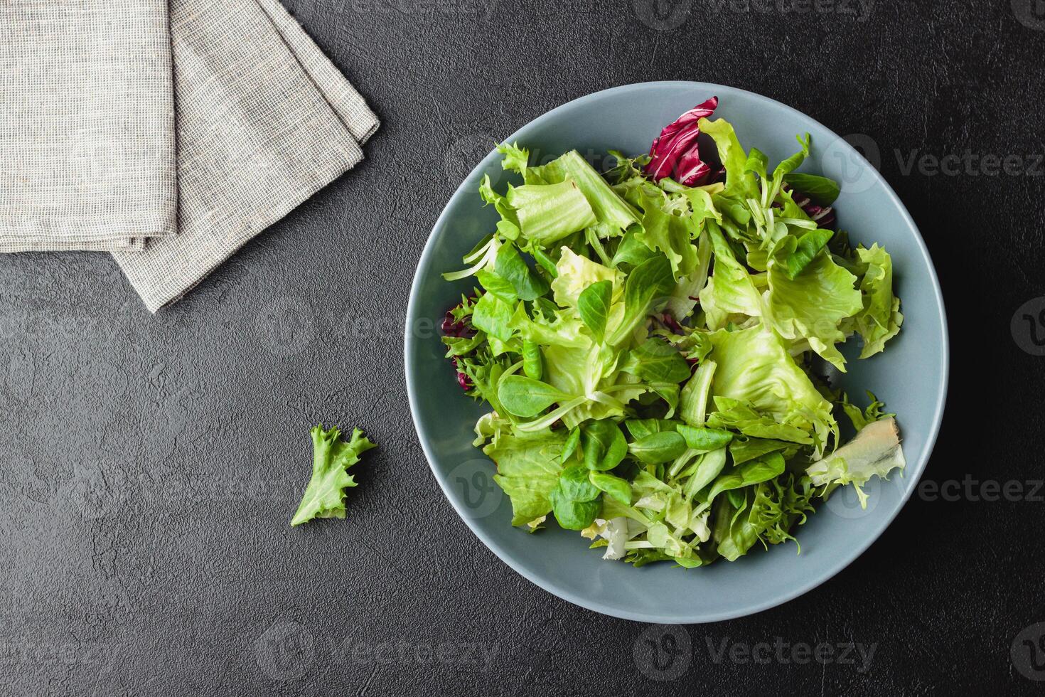 Green salad leaves in bowl on black table. photo