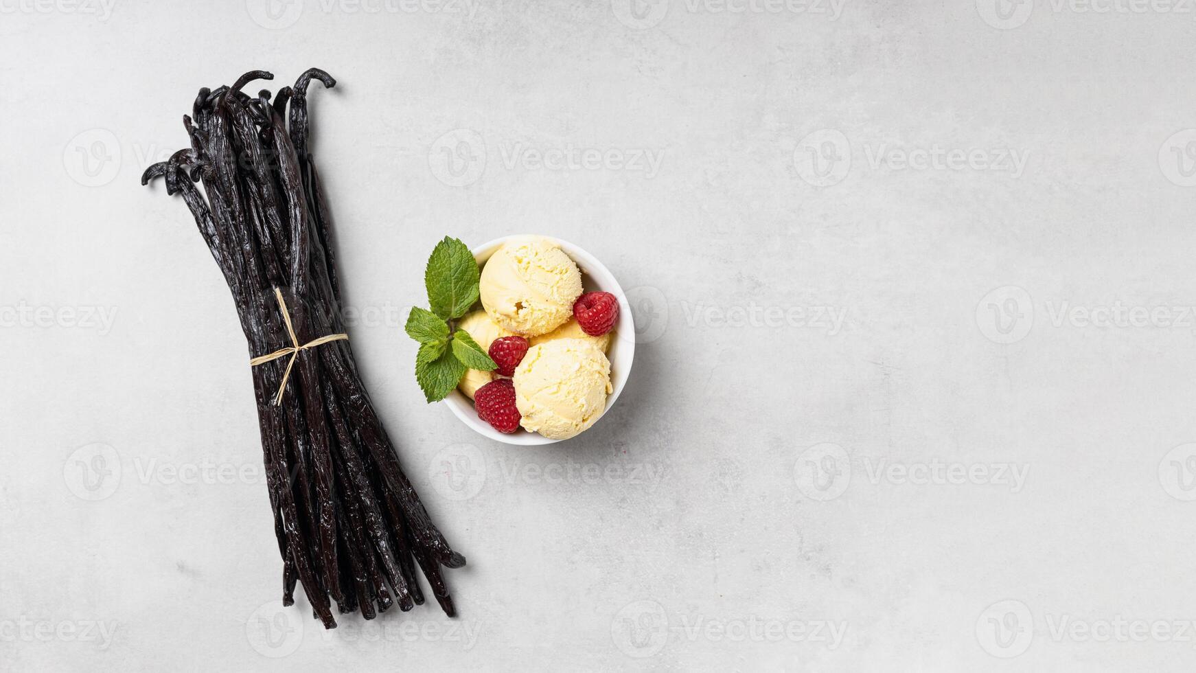 Vanilla beans and ice cream with raspberries on gray background photo
