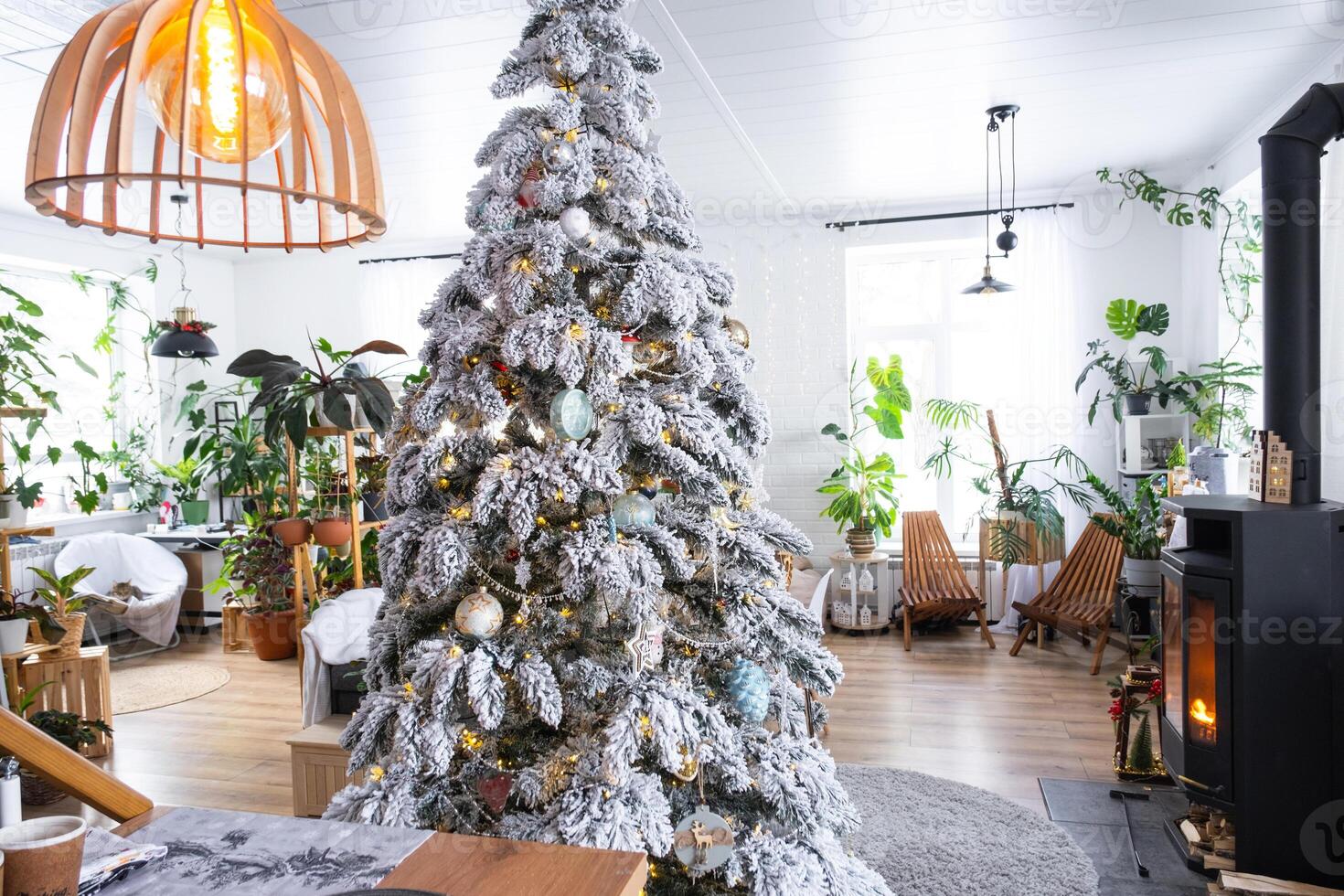 Festive Christmas decor in living room in a green house in the loft style with a retro wooden lampshade with a snowy Christmas tree and fairy lights. New Year, Christmas mood, cozy home. photo
