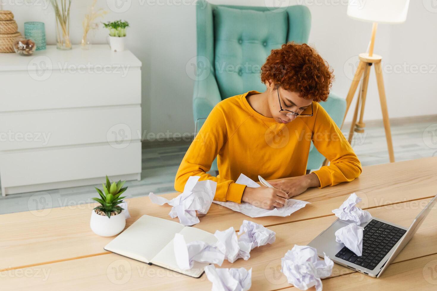 Serious African woman with crumpled paper having problem writing by hand document studying learning at home. Girl no idea sitting at workplace writing notes at office. Start up business deadline photo