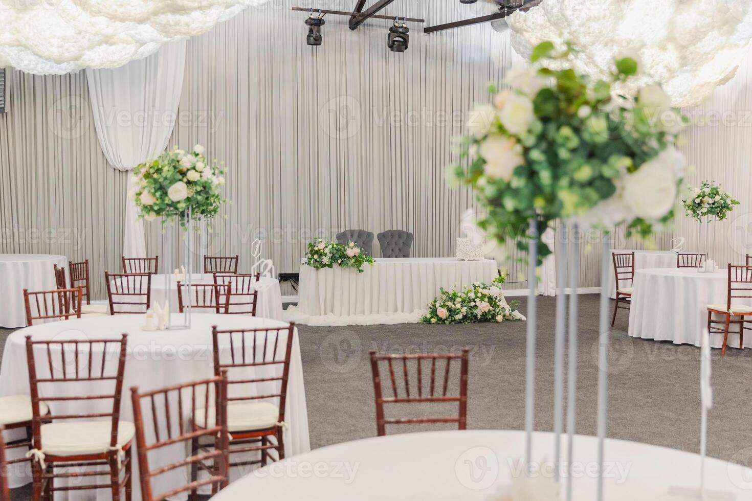 Decorated interior for festive event. Fancy table set for dinner with white flower composition in restaurant, luxury interior background. Wedding elegant banquet decoration arranged by catering service photo