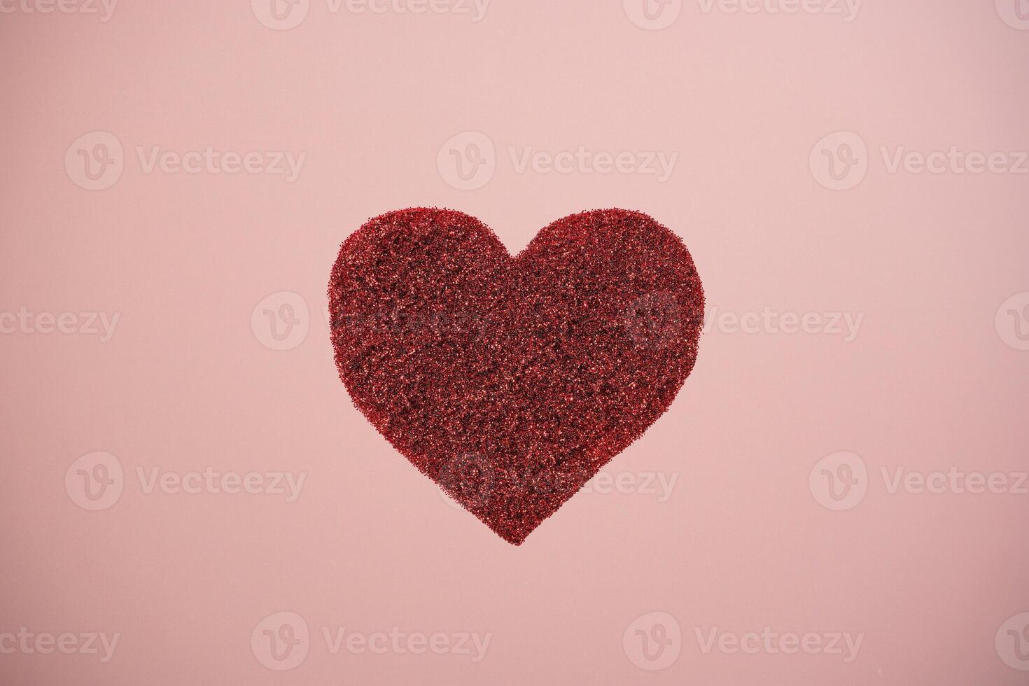 Red sparkle glitter heart on pink background. Minimalist holiday photo