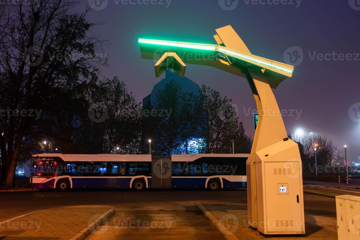 An electric bus stands at an empty bus stop and charges, a close up photo