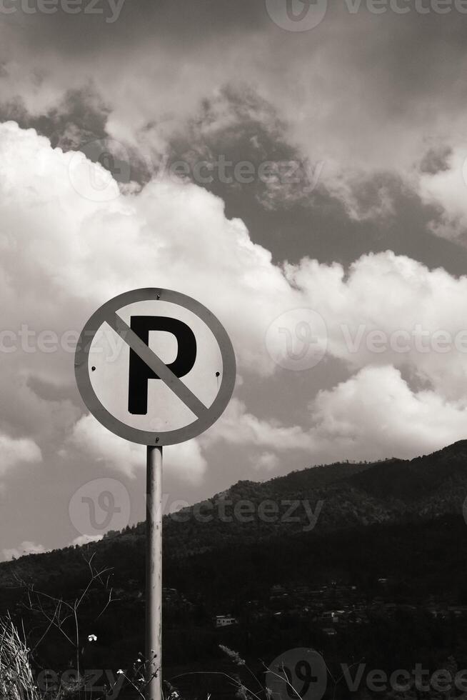 Monochrome Backgrounds No Parking sign post with cloudy sky and hill background. A silhouette of a round signpost on the side of the road. Copy Space. Graphic Resources. Road Traffic Signs. photo