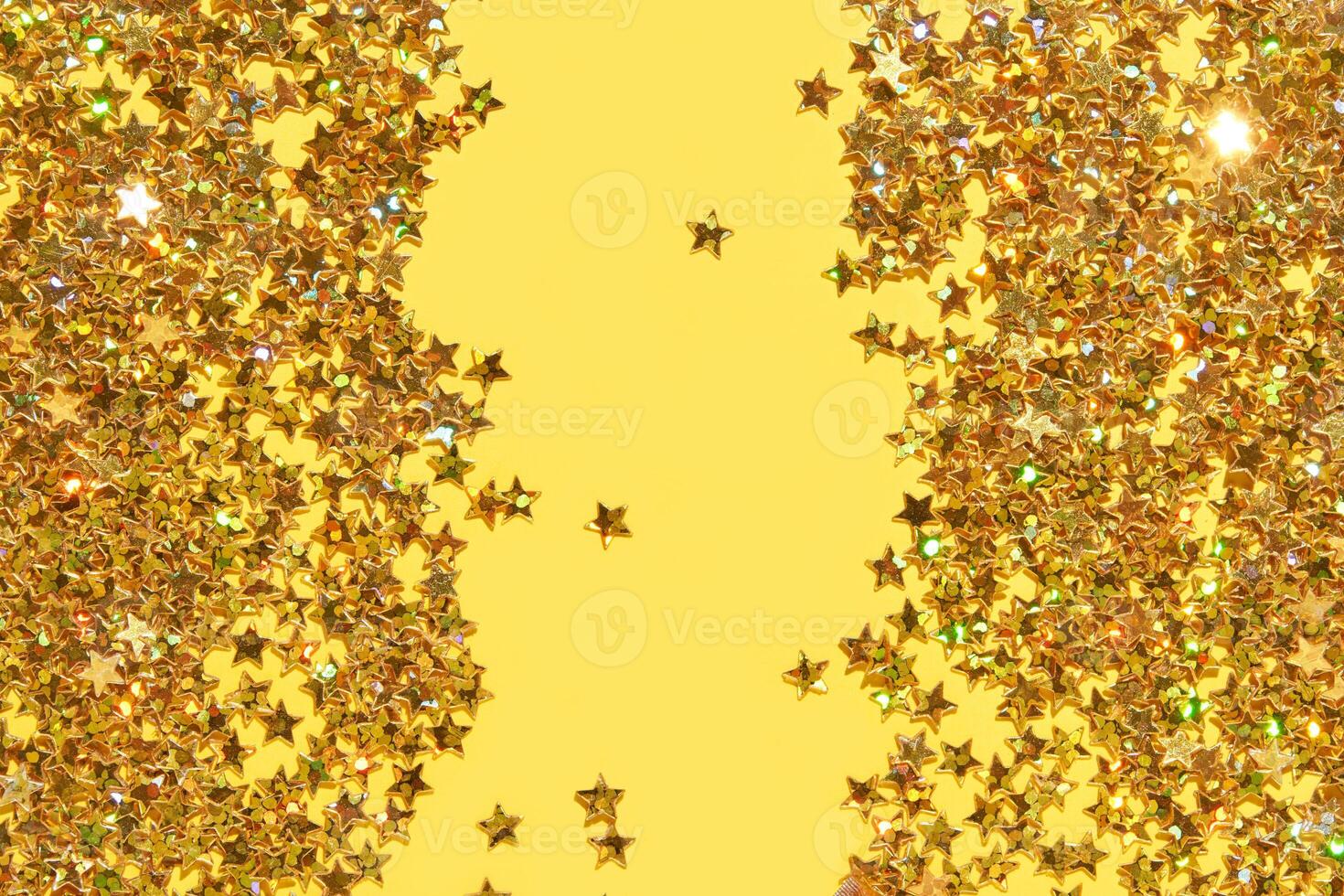 Sparkling gold star confetti on bright yellow background for festive celebrations and creative designs. photo