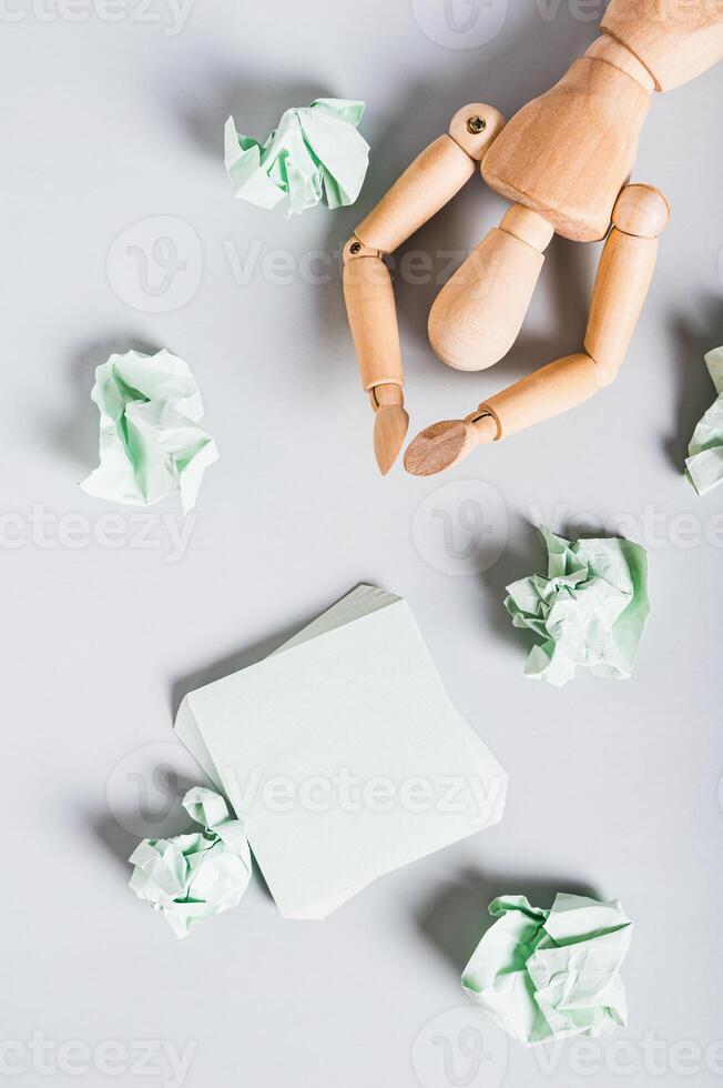 Burnt out man among crumpled note papers on desk top and vertical view photo