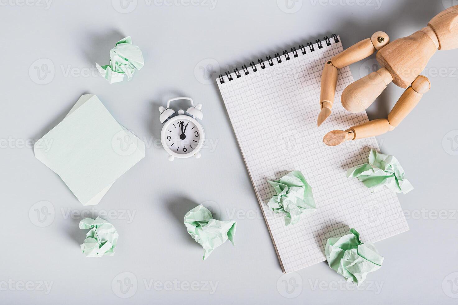 Burnt out man at work, notebook and alarm clock on desk top view photo