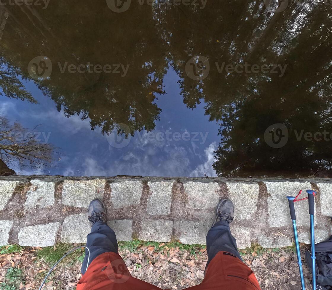 Legs of a hiker, seen from above, at the water's edge. Wildlife travel concept photo