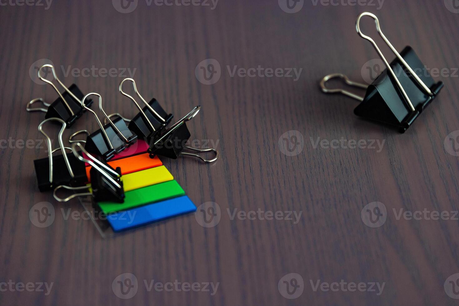 Stationery on the desk in the office. Multicolored bookmarks and paper clips. Copy space.. photo