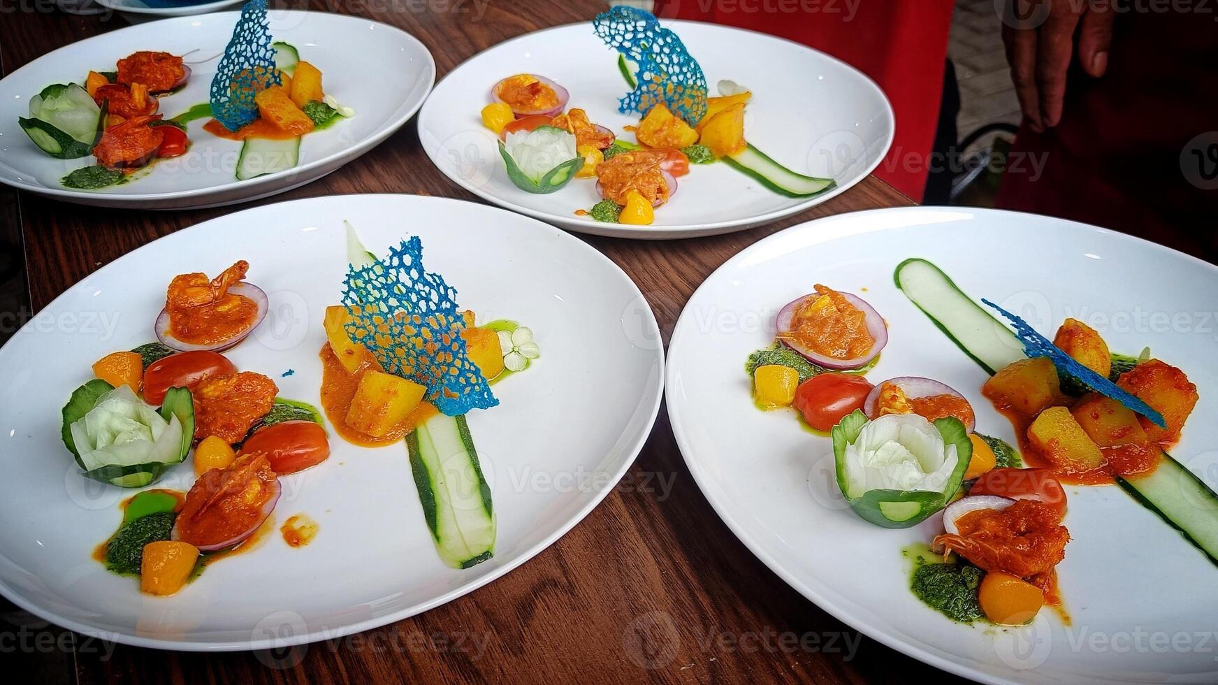 four plate Seafood Prawns in Red Sauce with Spicy Potato garnished with fresh cucumber photo