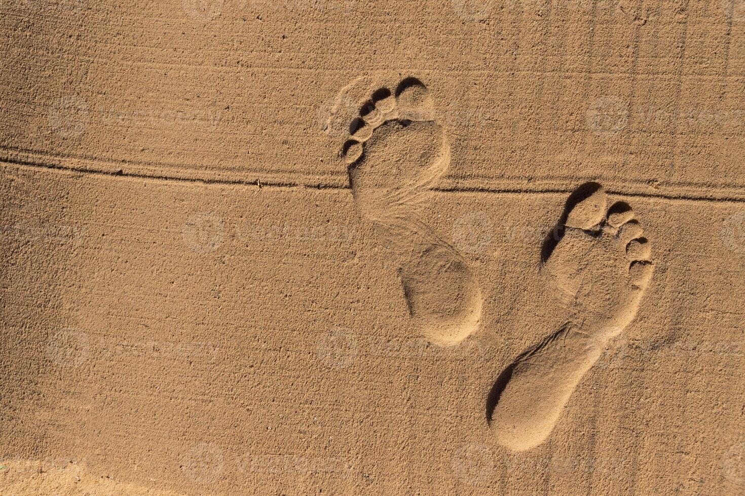 Two human footprints in the sand on the beach. Copy space photo
