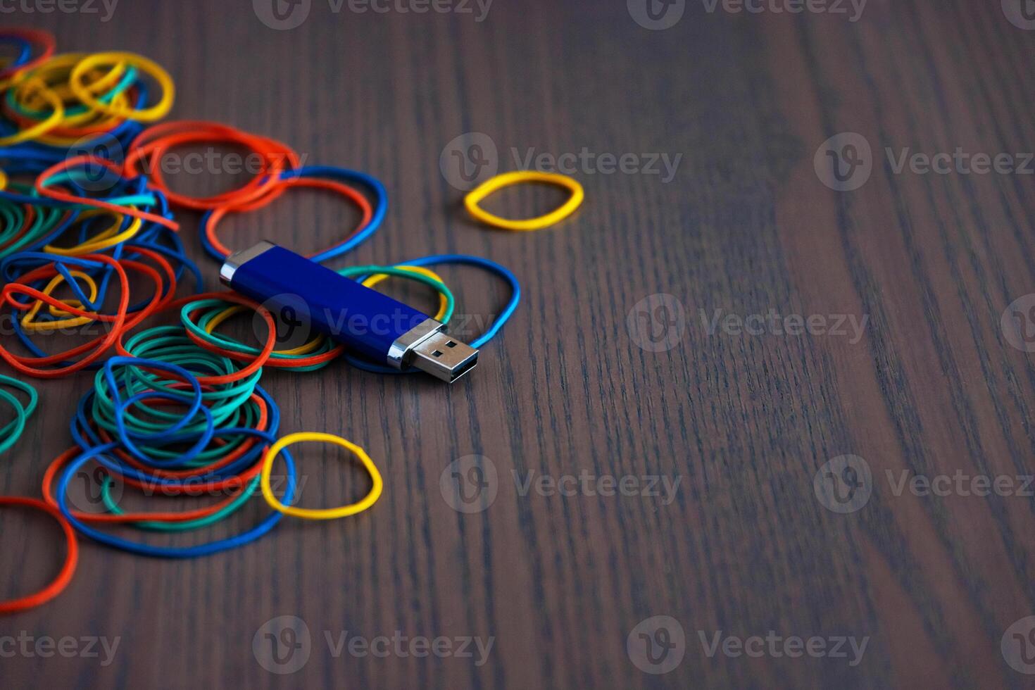 Stationery on the desk in the office. Multicolored rubber bands for papers and a flash card. Space for copying. photo