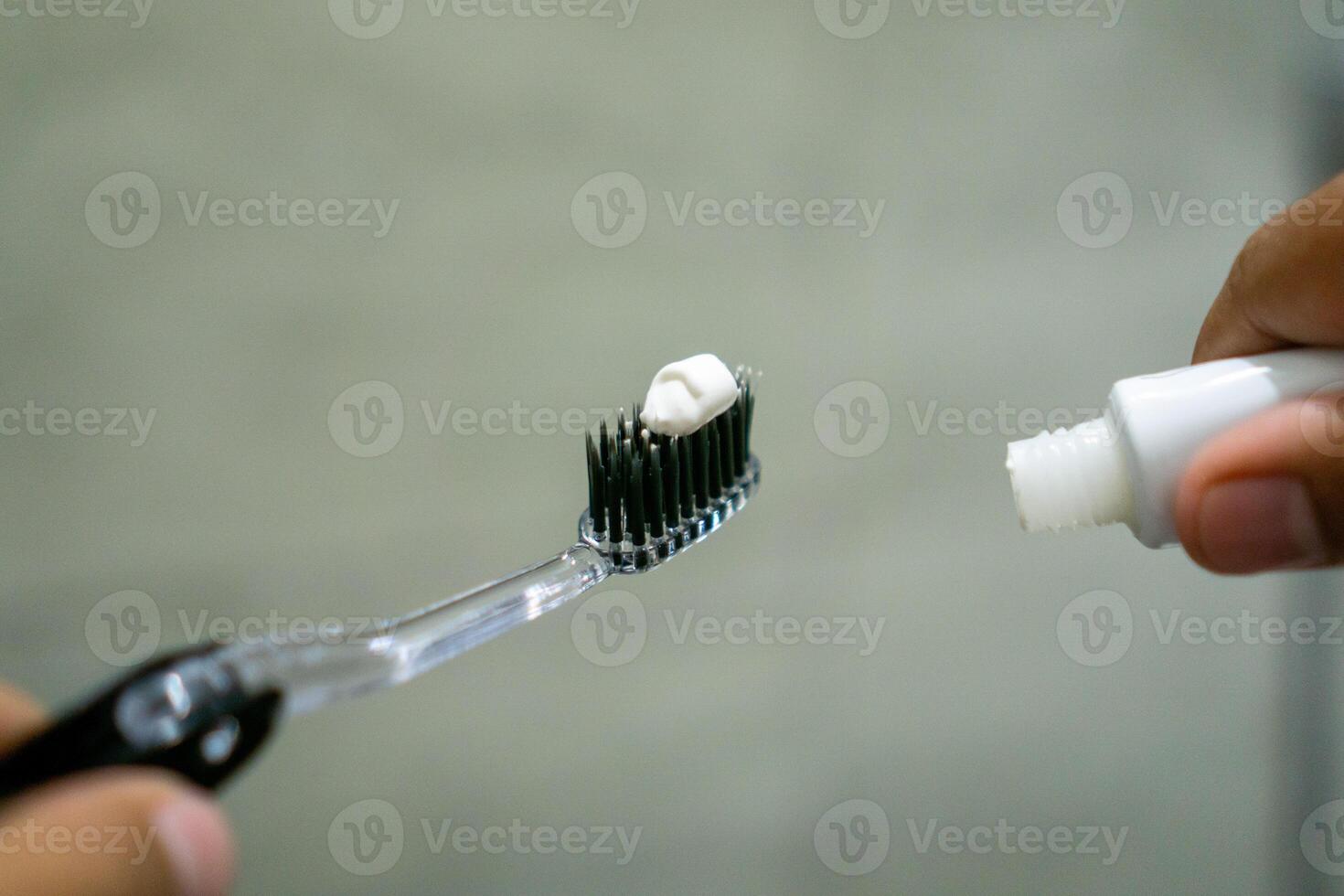 Close up of a hand holding a toothbrush with a toothpaste on the top. Oral cleaning concept. photo