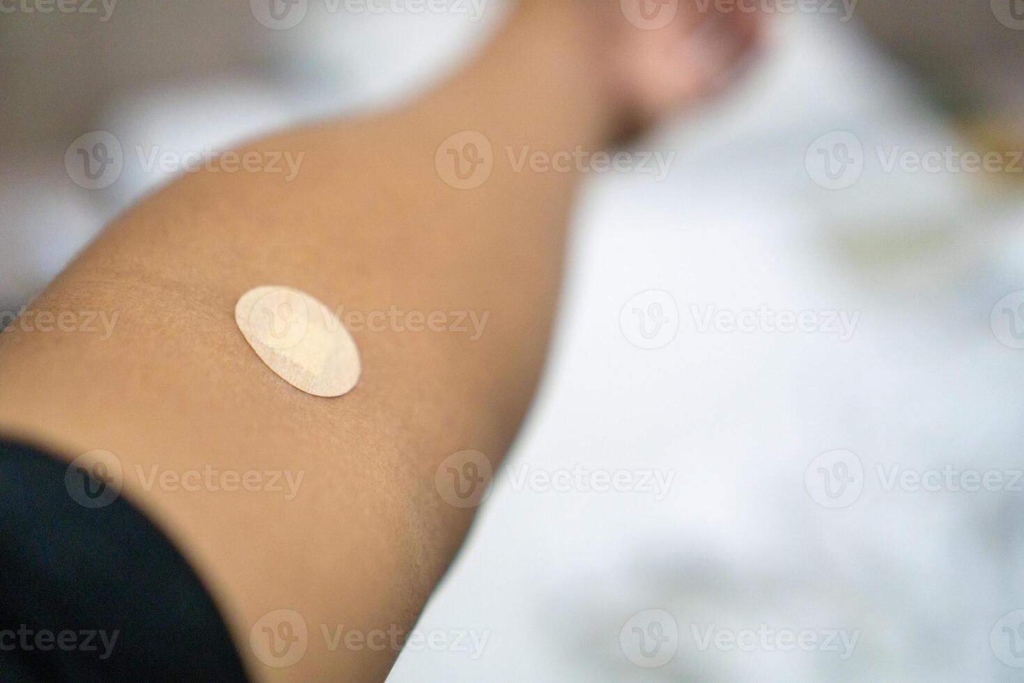Close up of medical tape on hand.. A medical adhesive bandage is placed on the injection site after blood sample collection to prevent bleeding and maintain cleanliness. photo