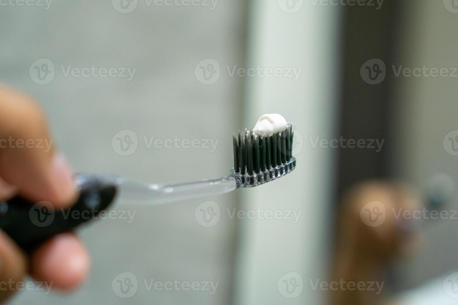 Close up of a hand holding a toothbrush with a toothpaste on the top. Oral cleaning concept. photo