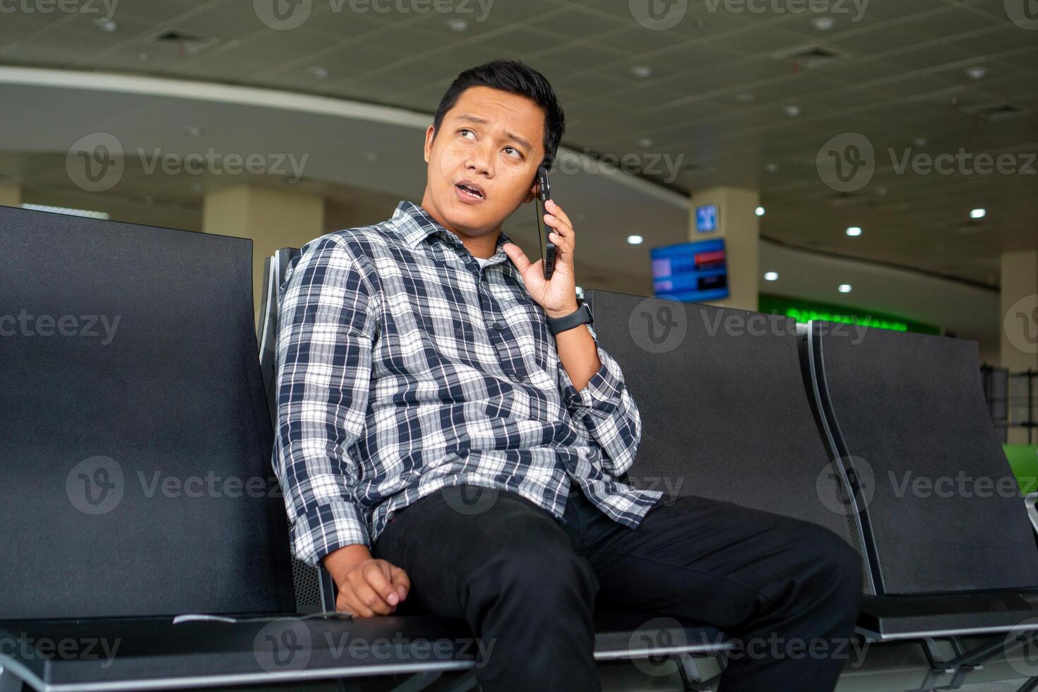 Asian man using mobile phone in airport waiting area. Male Tourist calling with his phone while waiting for departure in the airport. photo