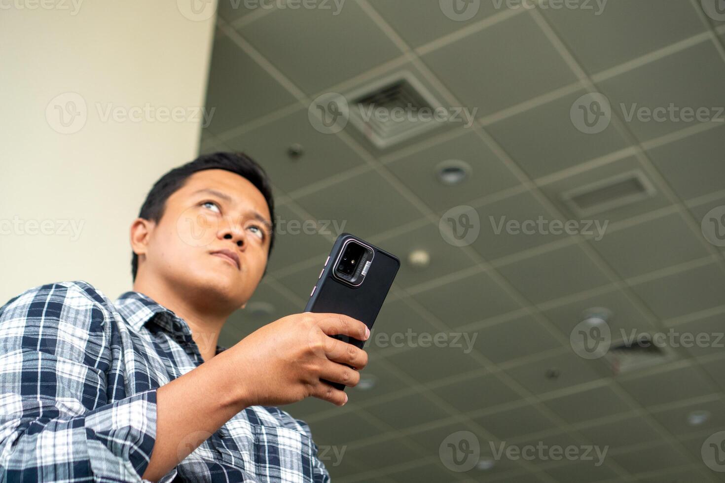 Asian man thingking while using mobile phone in airport waiting area. Male Tourist Sitting in the Airport waiting for plane. photo