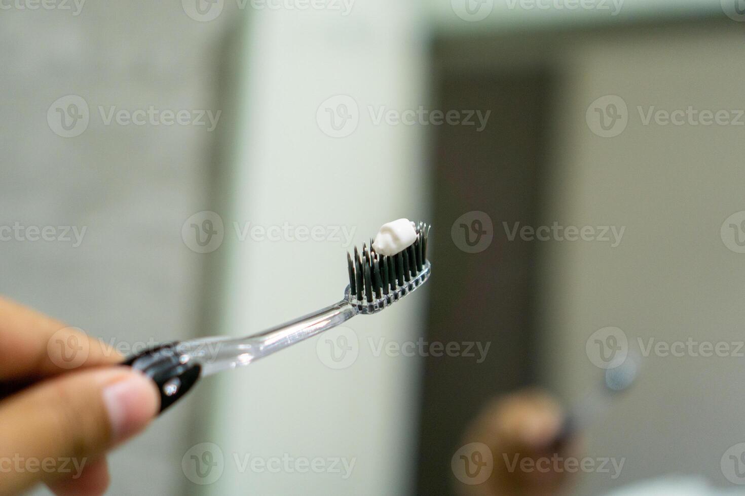 Close up of a hand holding a toothbrush with a toothpaste on the top. Oral cleaning concept. photo