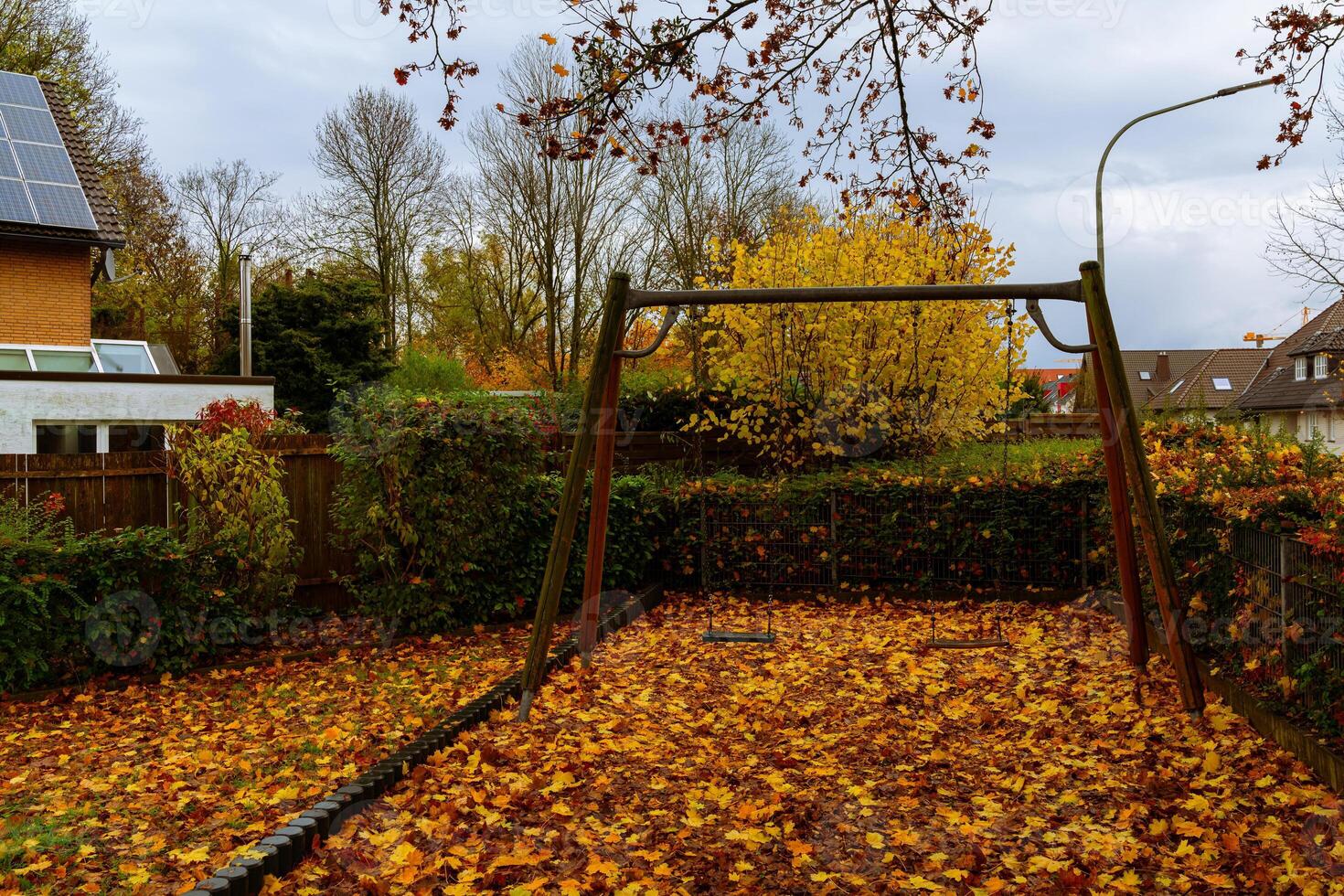 Autumn leaves cover empty swing set in quiet backyard photo