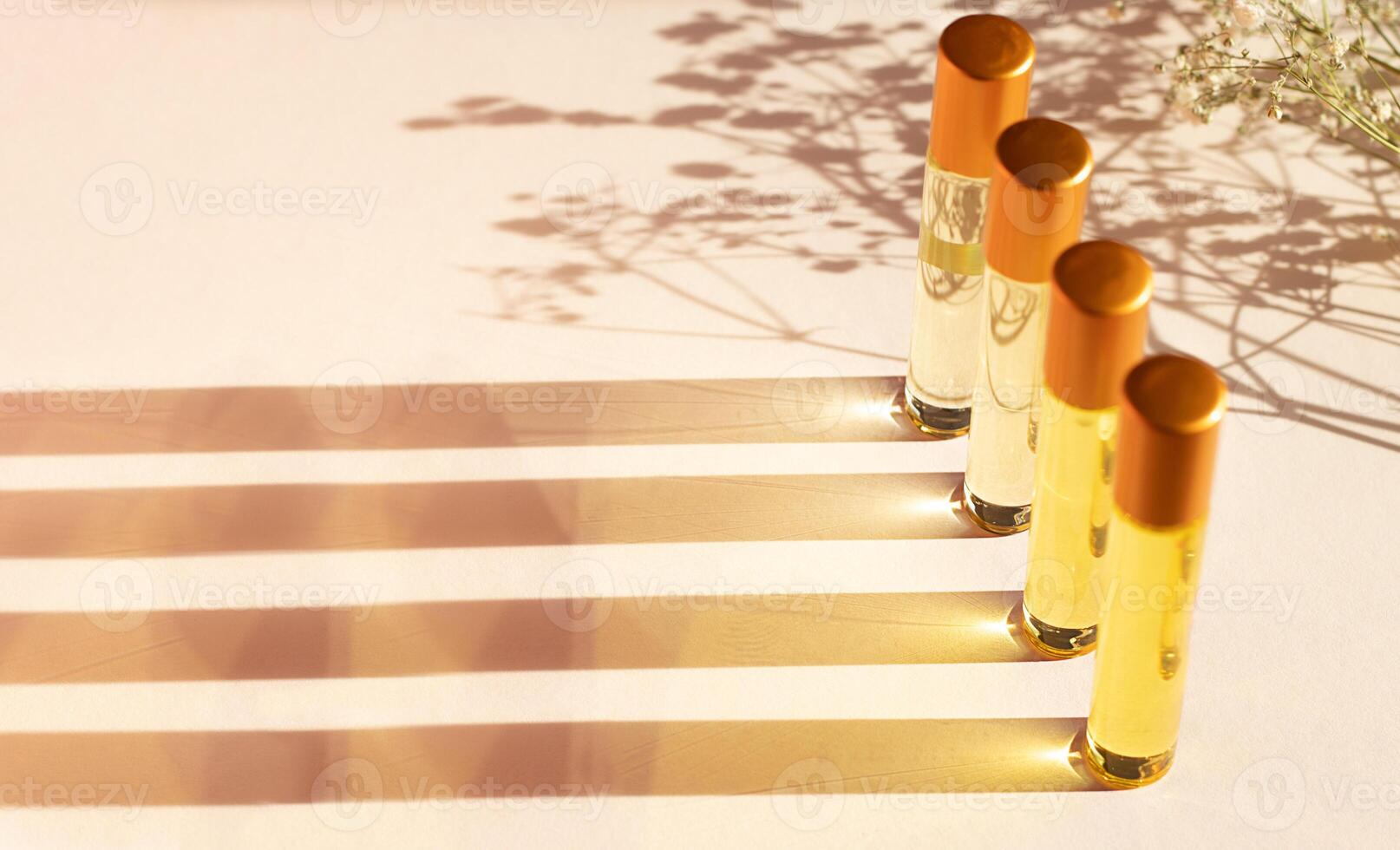 Oil perfume in travel bottles on a beige background with copy space, shadow from flowers. photo
