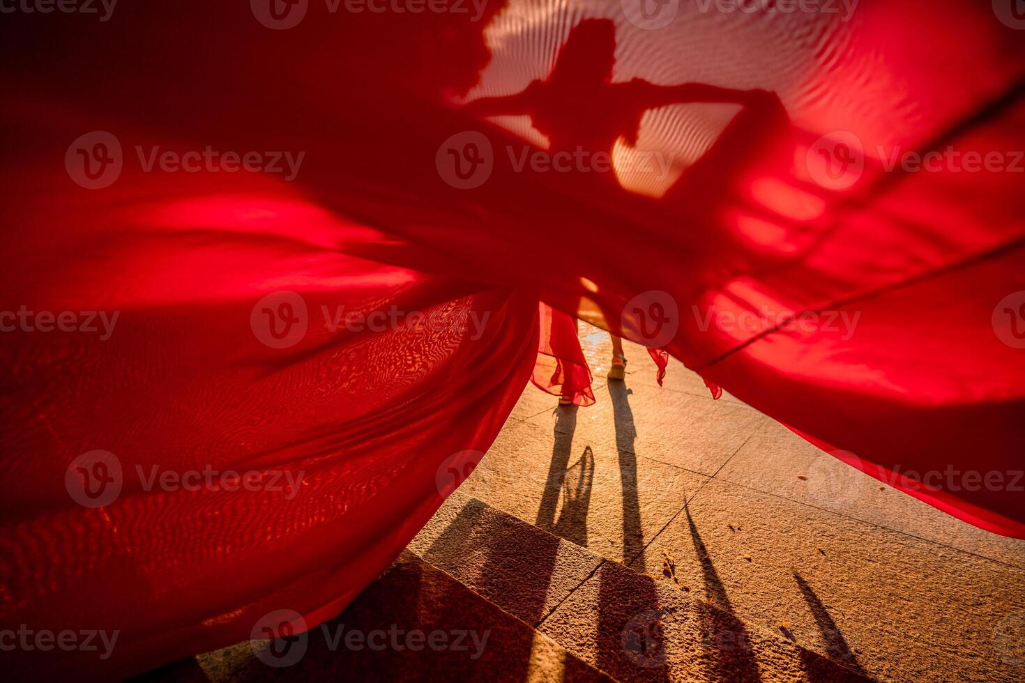 Sunrise red dress. A woman in a long red dress against the backdrop of sunrise, bright golden light of the sun's rays. The concept of femininity, harmony. photo