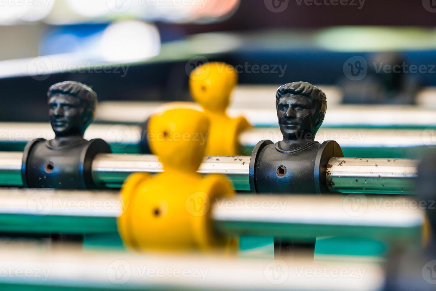Close-Up of Yellow and Black Foosball Players on a Table with a Vibrant Green Background Highlighting Teamwork and Competitive Spirit photo