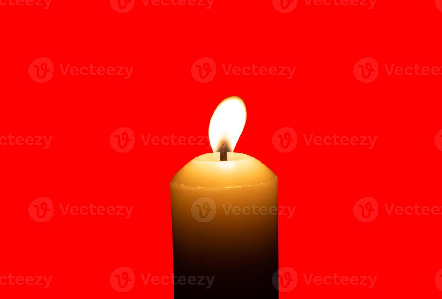 A single burning candle flame or light glowing on a big white candle isolated on red background with clipping path photo