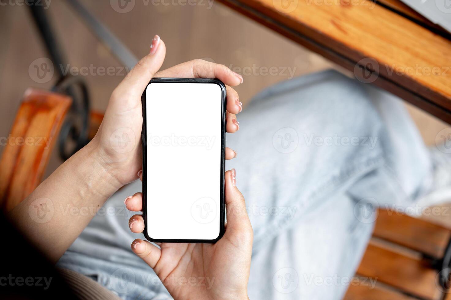 Awoman using her smartphone while sitting in a cafe. The smartphone with a white screen mockup. photo