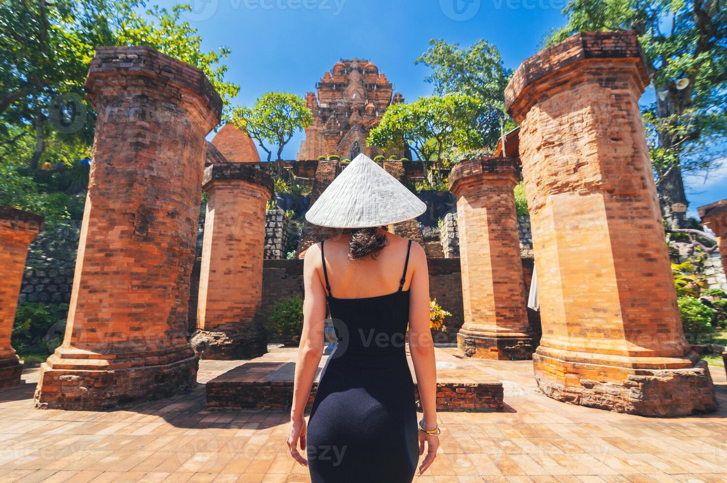 A female tourist stands with her back against the background View of Po Nagar Cham towers complex. photo