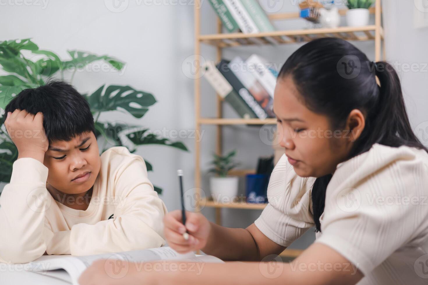 Female tutor helping little elementary school boy with homework during individual lesson at home, Sister helping boy writing lesson and learning to write, Education home school concept. photo
