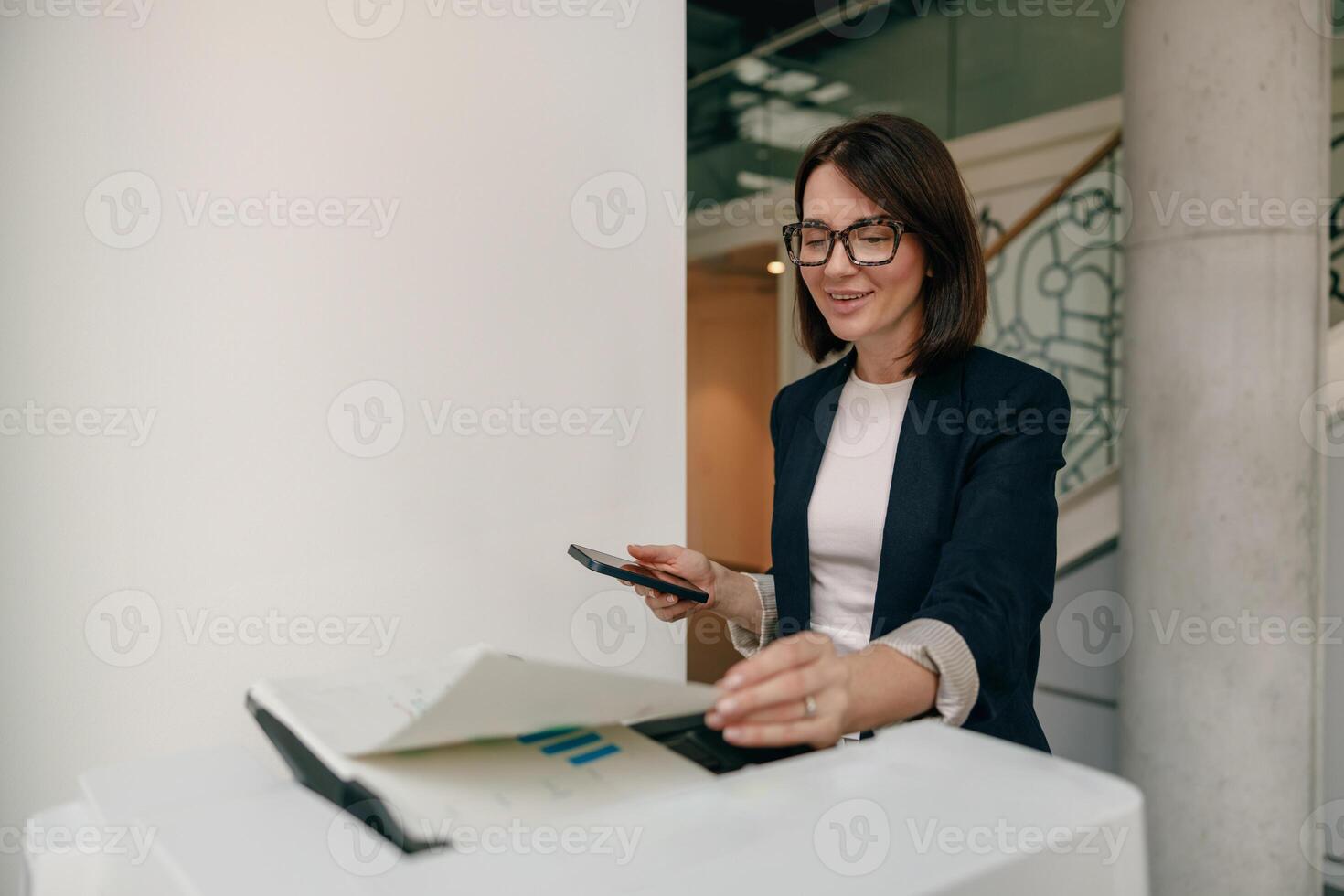 Professional Businesswoman Using Smartphone and Organizing Documents in Office with Efficiency photo