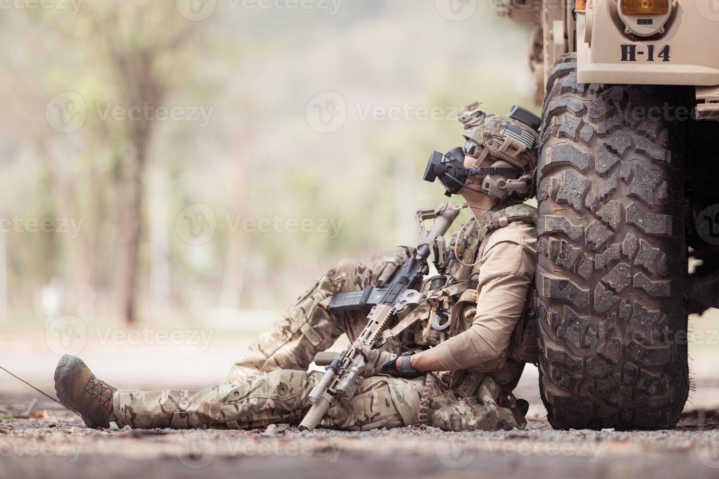 Soldiers in camouflage uniforms hold weapons ready to fire, By hiding on the side military communication vehicle photo
