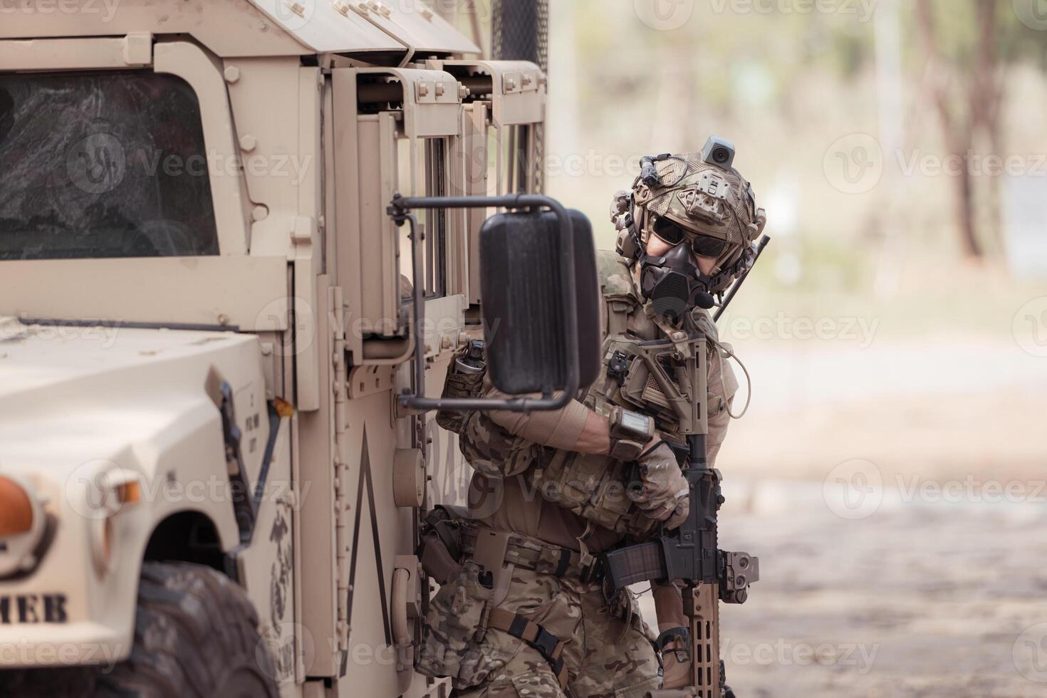 Soldiers in camouflage uniforms hold weapons ready to fire, By hiding on the side military communication vehicle photo