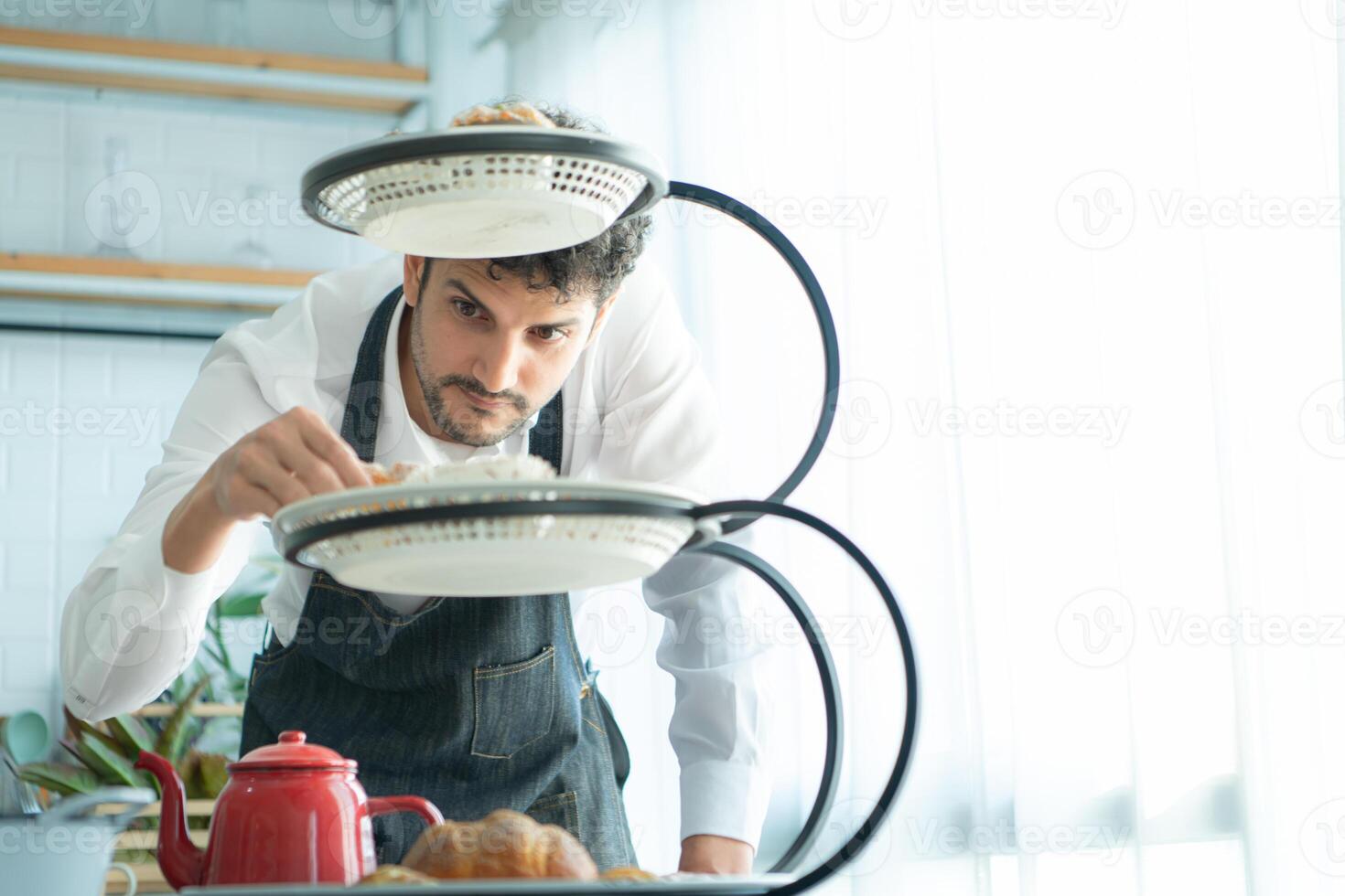 A young man puts on an apron to make dessert to eat with his wife. Checking the completeness of the finished dessert. photo