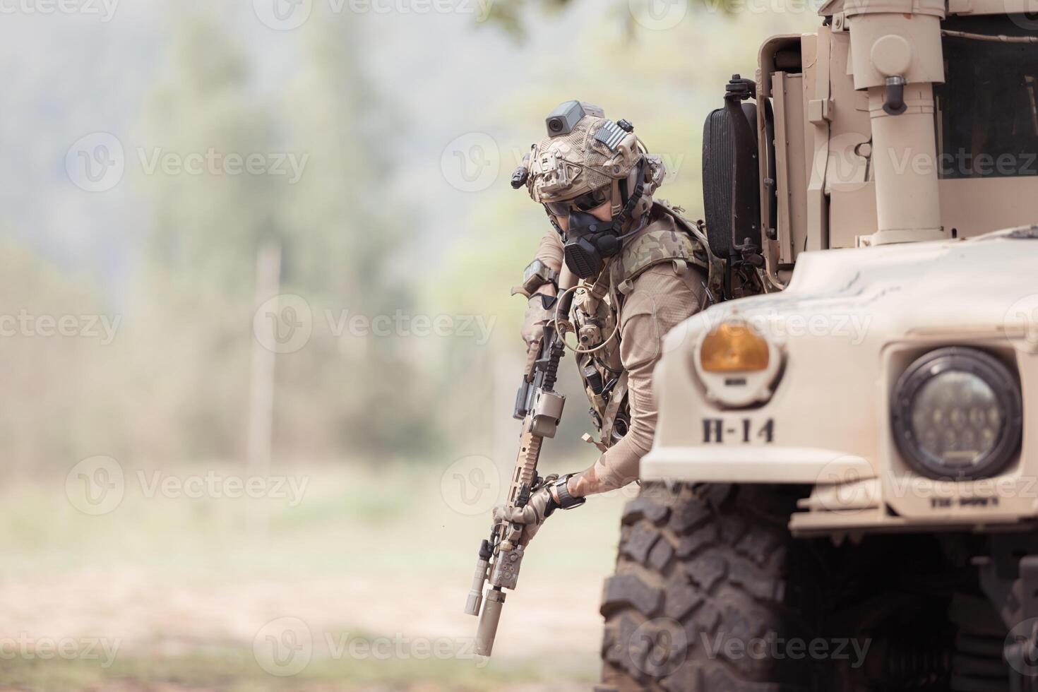 Soldiers in camouflage uniforms hold weapons ready to fire, By hiding on the side military communication vehicle photo