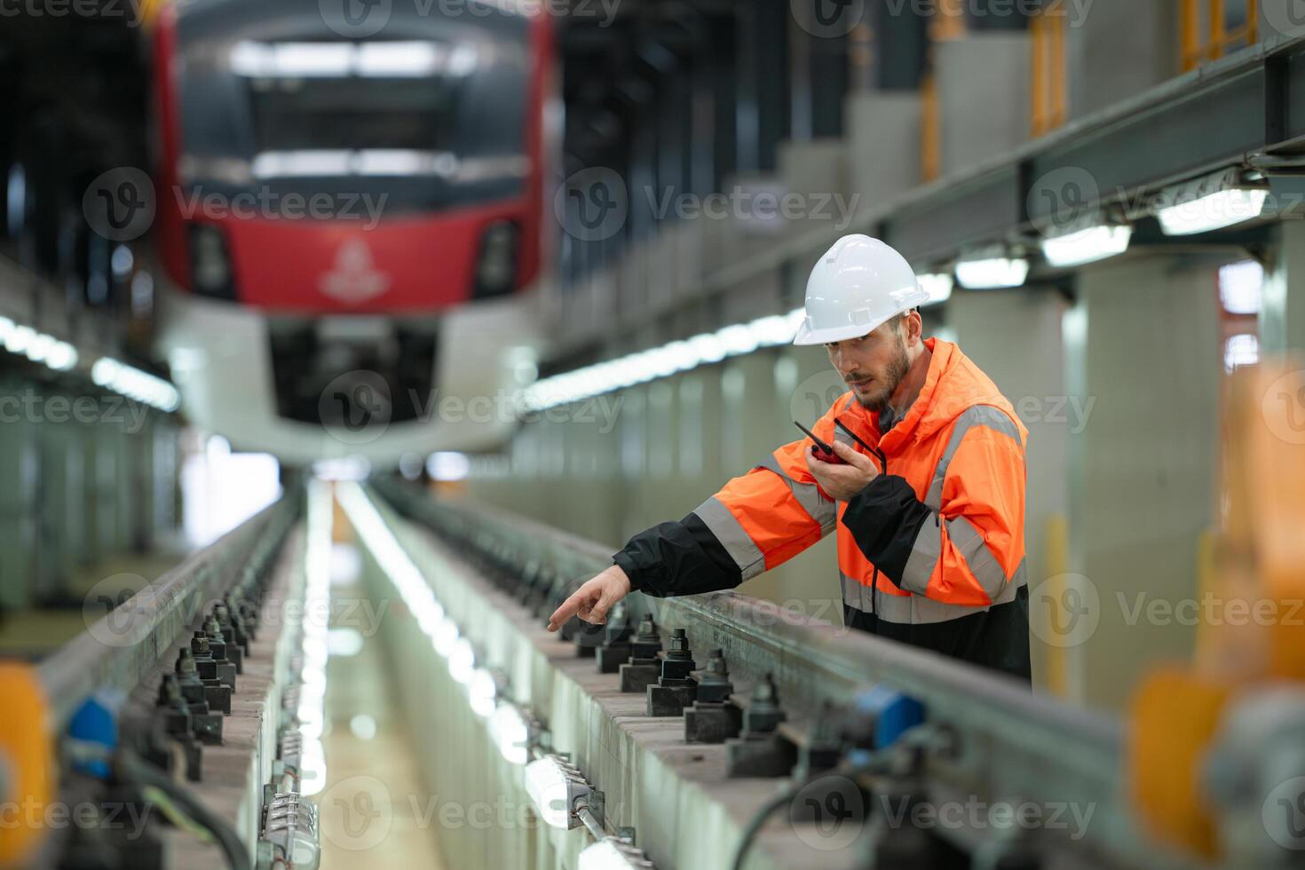 Portrait of a young male technician using a walkie talkie working and standing in a skytrain repair station. photo