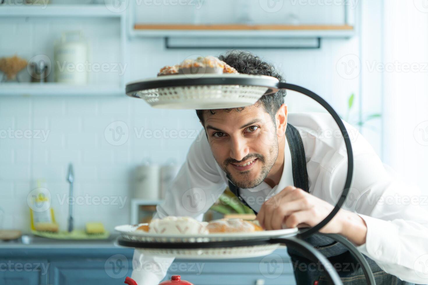 A young man puts on an apron to make dessert to eat with his wife. Checking the completeness of the finished dessert. photo